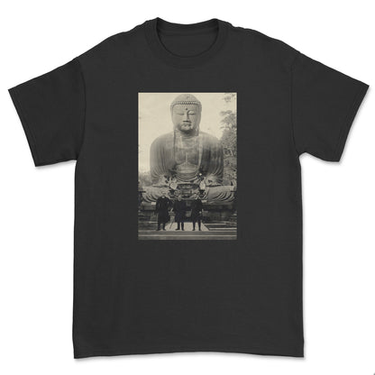 Black t-shirt with a graphic of a large Buddha statue and people in front on a white background